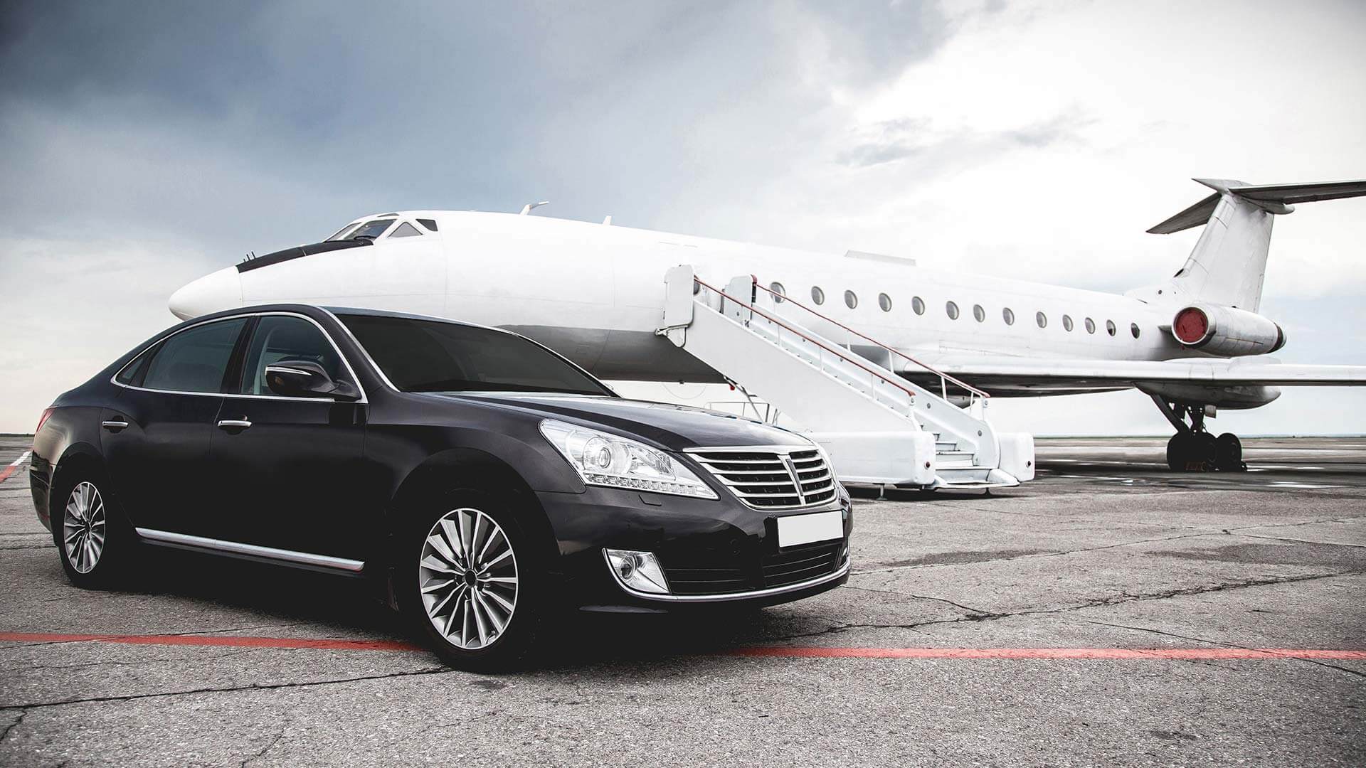 A luxury limousine parked at an airport curb for a short trip.